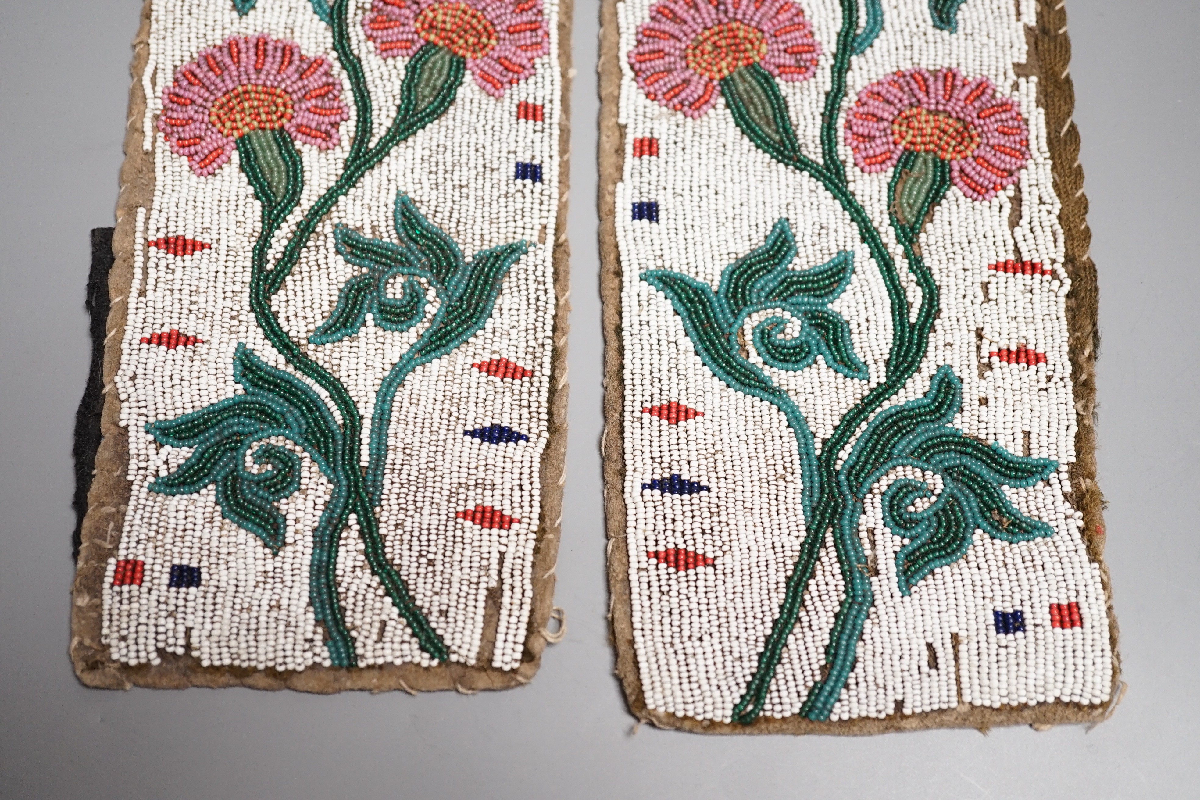 A fine pair of Native American Plains Indian rectangular beadwork panels, with floral designs and tribal markings, leather backing with remains of fabric edges, length 30cms